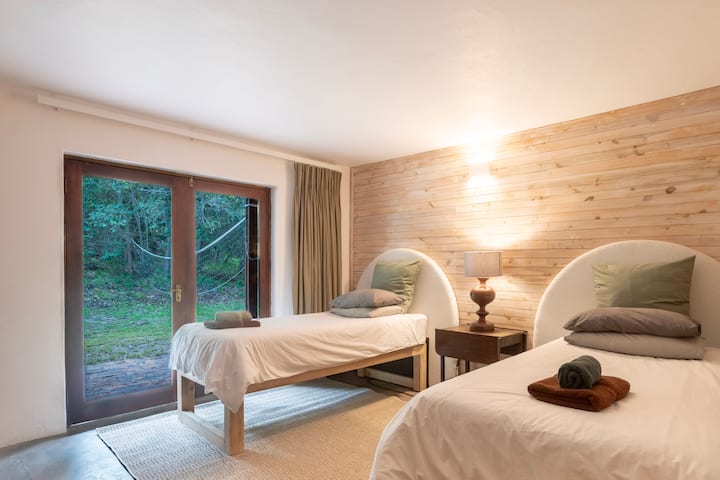 Dormitorio en el nivel inferior con acceso al jardín. Dos camas individuales con sábanas de algodón.