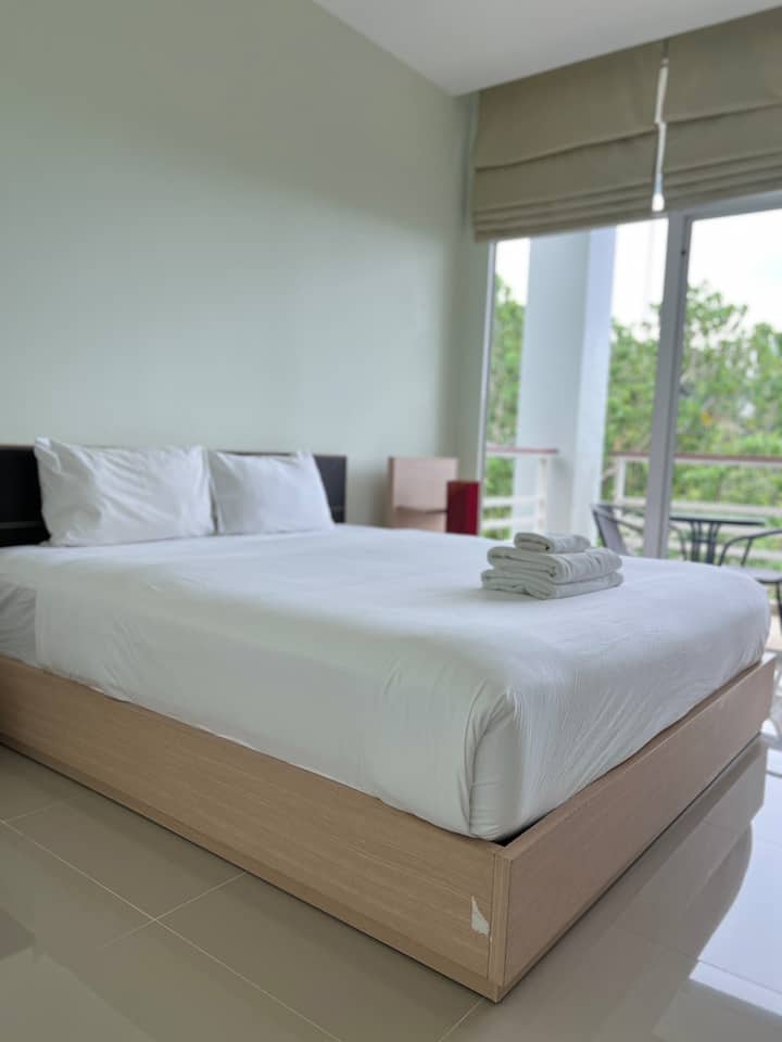 Dhomë gjumi e rehatshme me një krevat dhe ballkon.