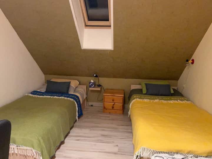 שתי מיטות יחיד, כורסה לקריאה נוחה ושולחן.