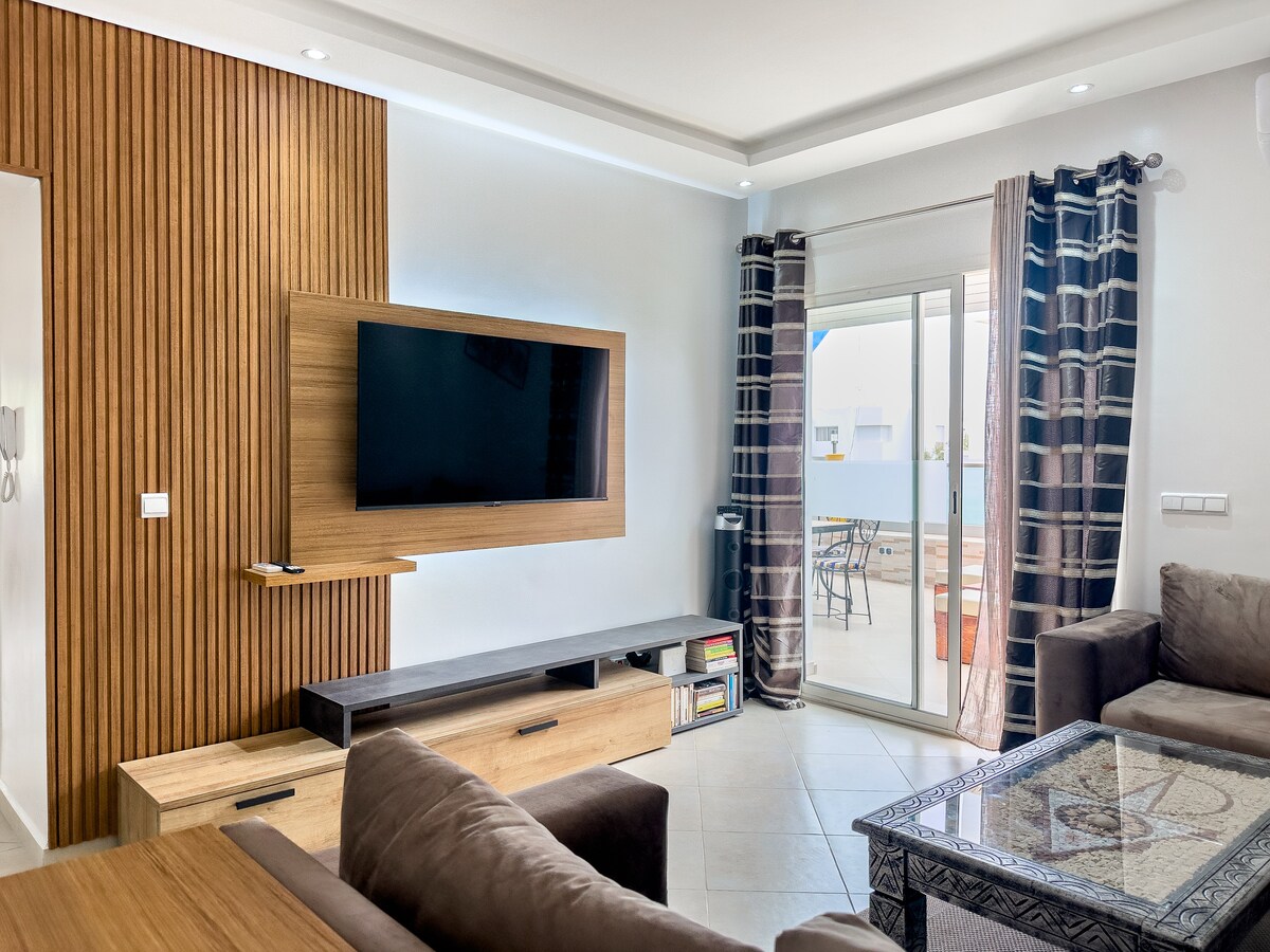 ️ Dhoma e ndenjjes
Dhomë ndenjjeje e ndritshme me divan qosheje, televizor me ekran të sheshtë, ajër të kondicionuar dhe qasje të drejtpërdrejtë në tarracë. Atmosferë moderne dhe e ngrohtë. ✨