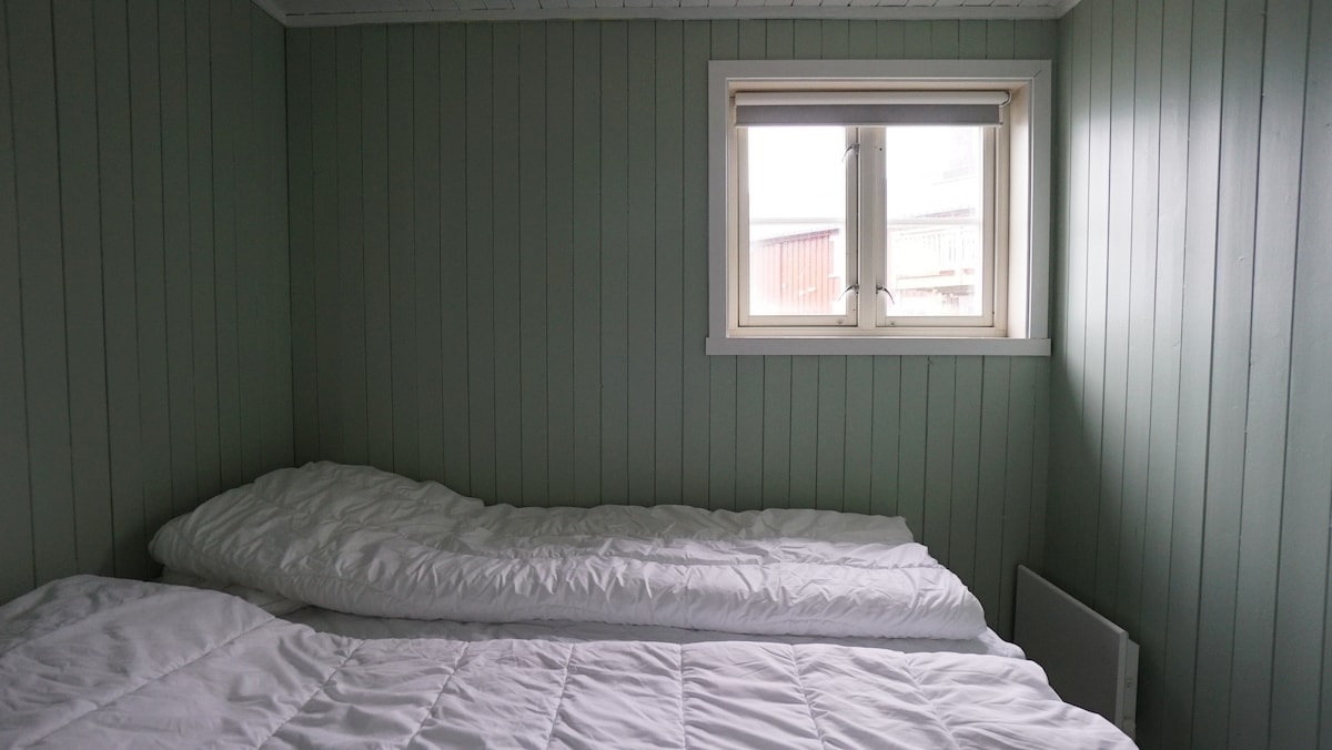 חדר שינה עם שתי מיטות יחיד ונוף לנמל.