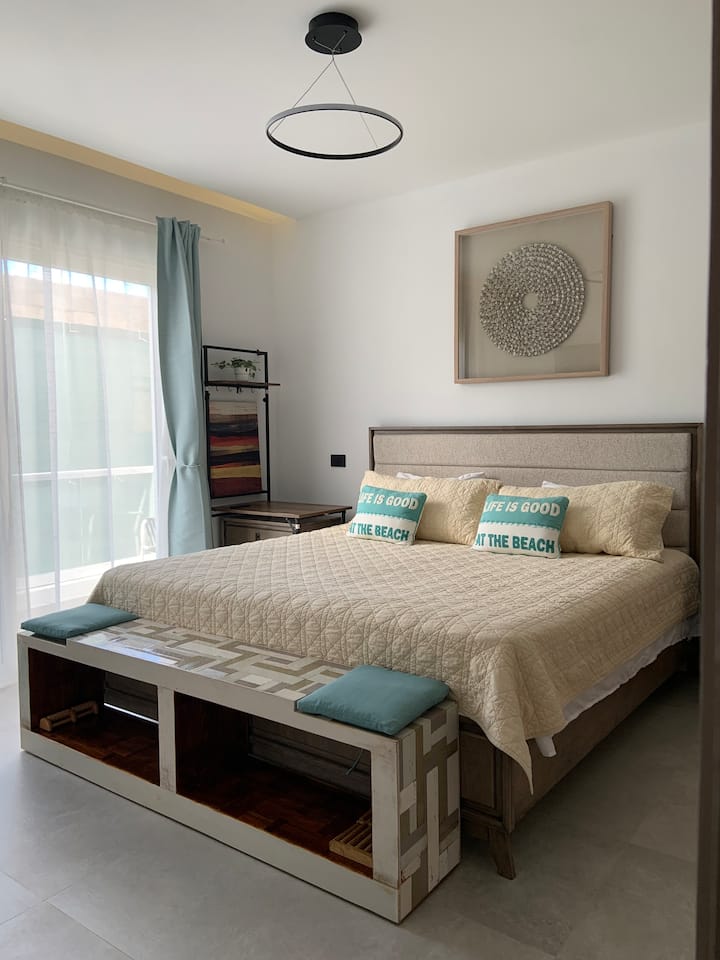 Comfortable King-size bed (193×202 cm or 76”x80”) | Bench |  Foot massagers |  2 nightstands with 2 drawers and built-in phone chargers |  Double closet |  55” smart TV |  Wall desk workstation | Lamp | Floating drawer | Balcony with 2 chairs | A/C