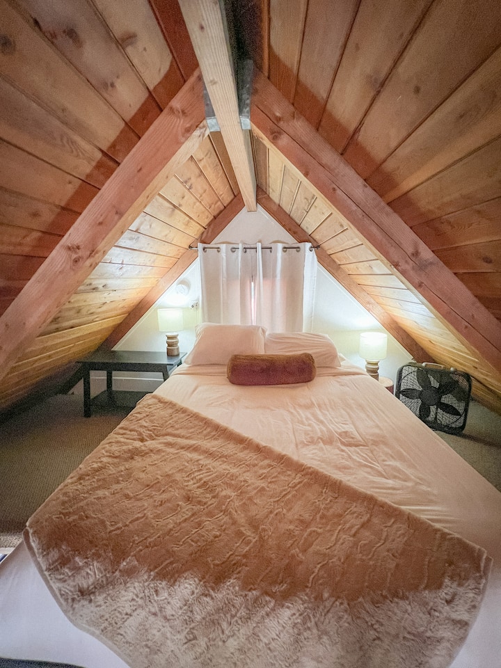 2階のロフトオックスボウキャビンのロフトベッドルームには快適なクイーンベッドがあり、快適なリトリートだけでなく、下のファミリールームを見下ろすユニークな視点も提供しています。クイーンベッド付き