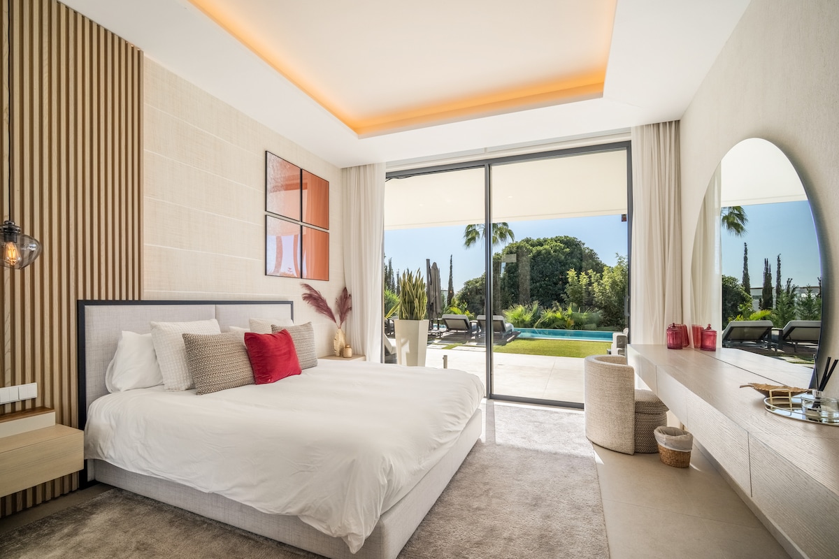 Prabangus sodas: elegantiškas miegamasis su vonios kambariu, stiklinėmis sienomis ir sklandžiu patekimu į lauko baseino zoną.