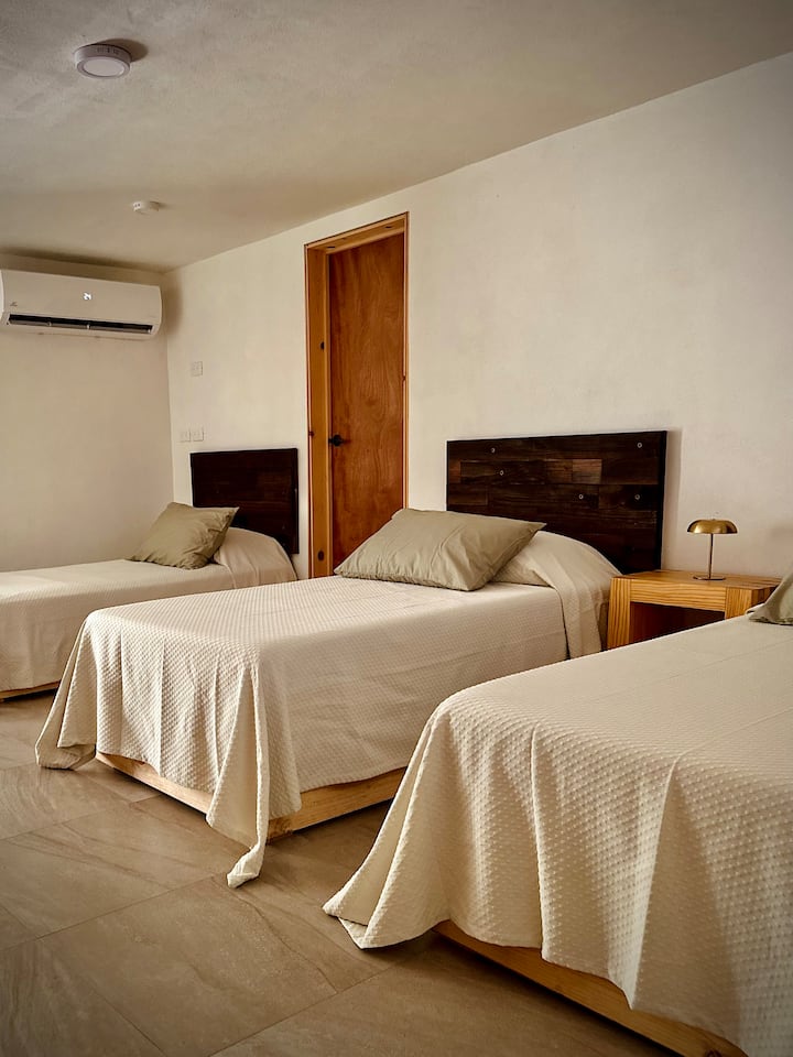 Vitanda vitatu vya mtu mmoja vilivyovaa nguo laini ambazo zinakumbatia mwili, zikivutia mapumziko ya kina. Meza ya usiku, karibu na fanicha maridadi ya mstari, tani hafifu hufunika sehemu kwa utulivu na amani kabisa.