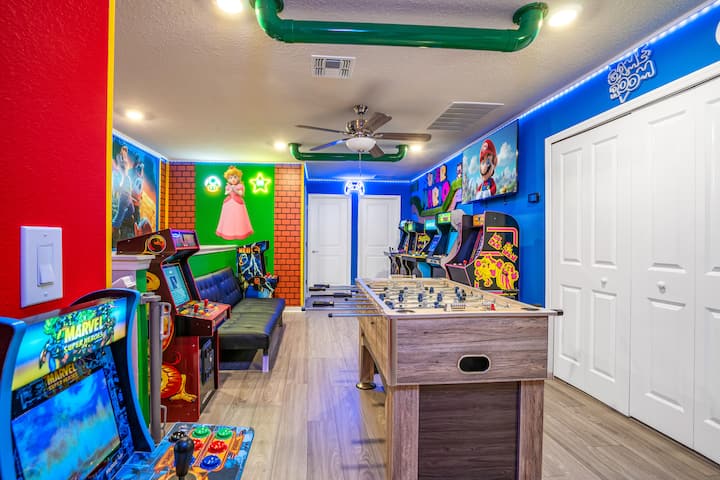 استمتع بلعبة Super Mario المثيرة في غرفة الألعاب! تتميز هذه المساحة بآلات ألعاب الأركيد وطاولة كرة القدم ولوحات فنية على الجدران ومصابيح نيون وتلفزيون كبير وديكور ممتع وأجواء ألعاب نابضة بالحياة، مما يجعلها مثالية لمغامرة غامرة في مملكة الفطر مع المتعة