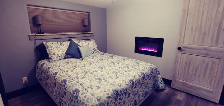 Dormitorio principal 1 con cama tamaño queen, armario de tamaño completo, televisión, chimenea eléctrica incorporada y baño de tamaño completo.