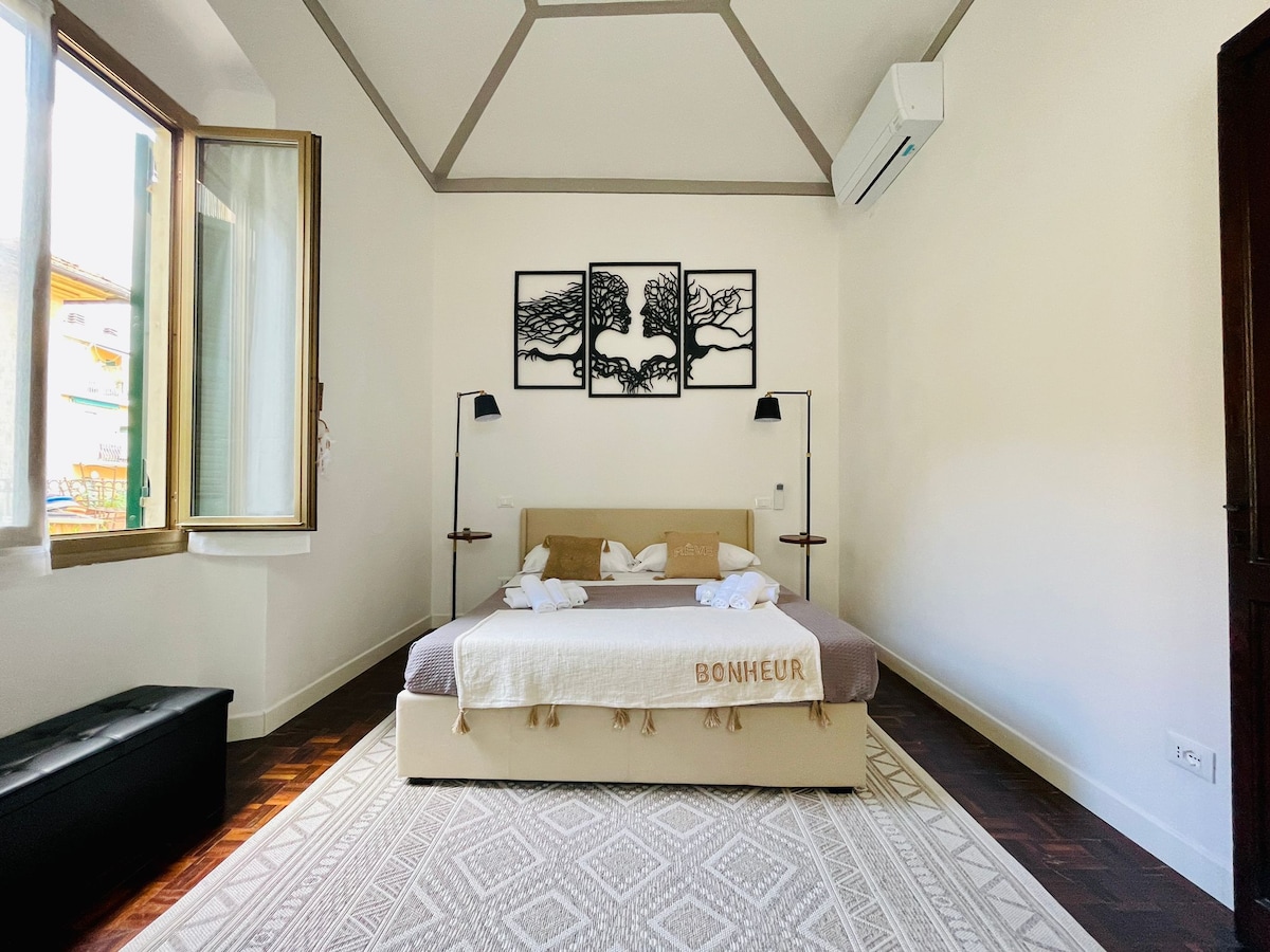 Zbulo sharmin e dhomës kryesore të gjumit nga një kënd tjetër, duke theksuar dekorin elegant të dhomës, tavanet e larta të ajrosura dhe dritën e bollshme natyrore për një pushim të qetë.