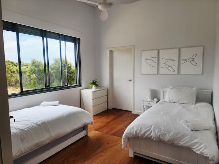 Guest bedroom 2 with two King single beds.
Native bushland views and ocean glimpses