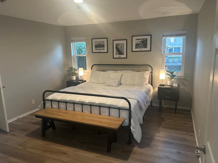 La chambre principale a un lit King size avec deux tables de chevet et des lampes supplémentaires de chaque côté et un grand ventilateur de plafond 