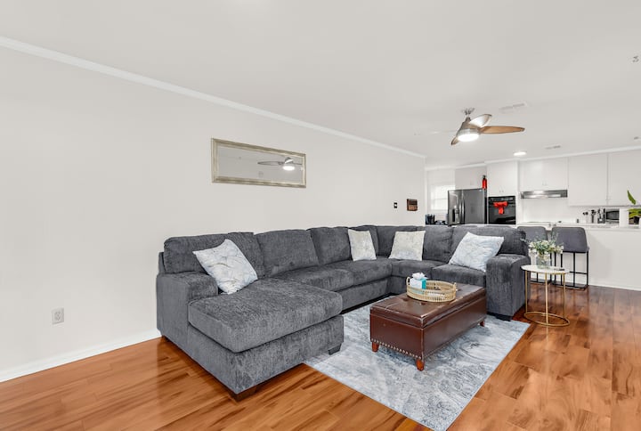 تتمركز أريكة كبيرة مقسمة في غرفة المعيشة، وتوفر مساحة جلوس واسعة للعائلات لتجتمع وتسترخي وتقضي الوقت معًا بشكل مريح.