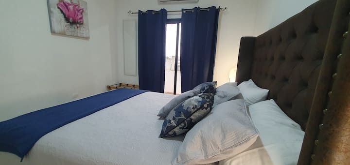 Habitación equipada con 1  confortable  cama  Queen con moderno respaldo y 4 cómodas almohadas y cojines, 2 mesas de noche con sus respectivas lámparas, 1  porta maletas, aire acondicionado, espejo. Puertas corredizas con acceso a pequeño balcón.
