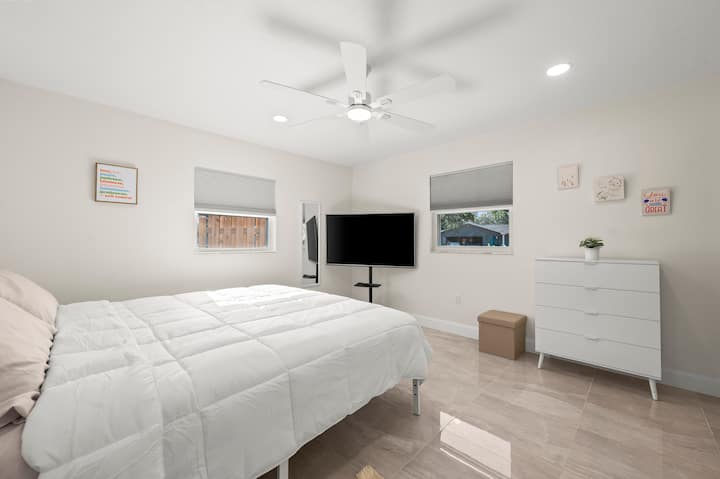 This room has a work space with desk, large movable TV, and a large hanging closet.