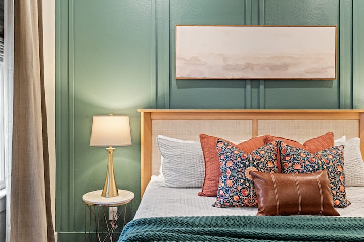 Rest easy in this serene master bedroom with a plush king bed, cozy linens, Quince cotton comforter, stylish accent wall, and wall-mounted 65” smart TV.