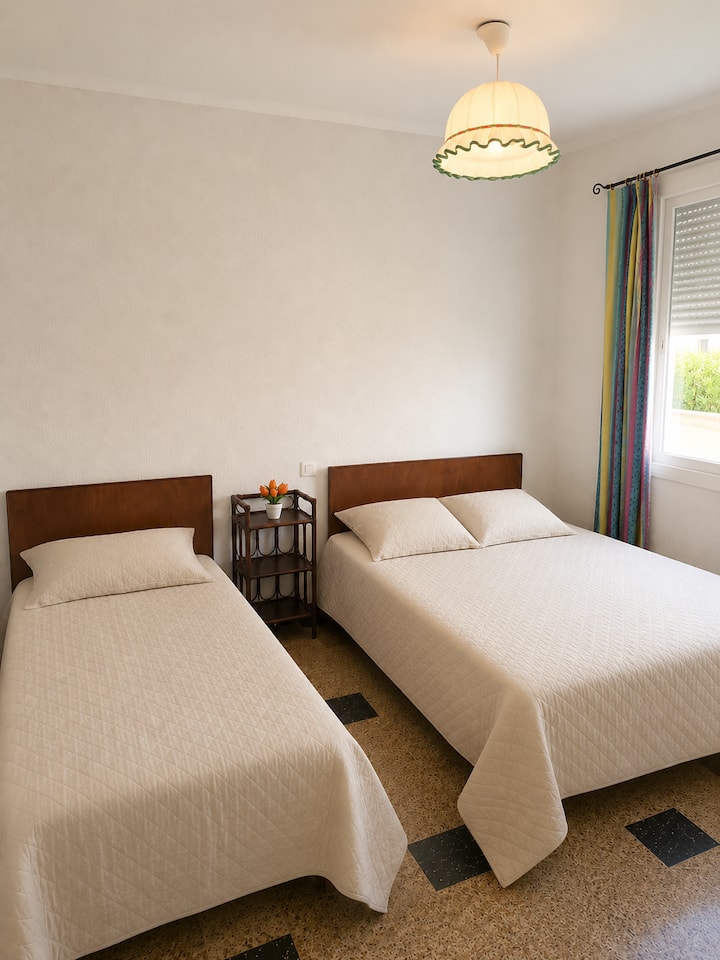 Ein helles und großes Schlafzimmer mit einem Bett von 140 x 190 und einem Bett von 90 x 190, einem großen Fenster, einem Nachttisch, einem Schrank. 3 quadratische Kissen 65 x 65