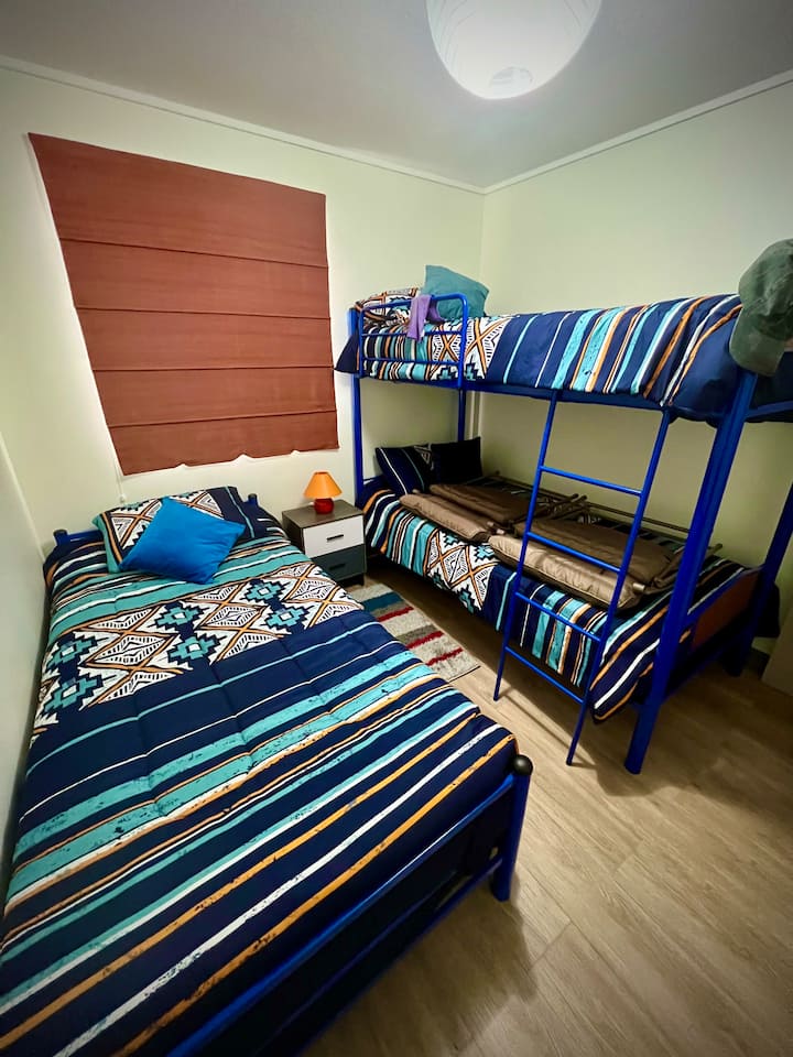 Habitación con tres muy cómodas camas. Dos en camarote, la superior con escala y baranda de seguridad. Esta habitación tiene acceso a baño independiente a sólo un par de pasos. 