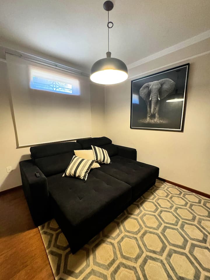 ห้องพักพร้อมเตียงโซฟาคู่ทีวีและพัดลมมือถือ มีพื้นที่สำหรับฟูกนอนคู่บนพื้น 