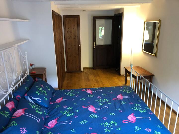 Спална соба со двоен кревет, гардероба, поглед кон градината 