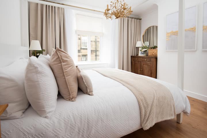 Serene, light-filled bedroom with luxe bedding and chic chandelier.