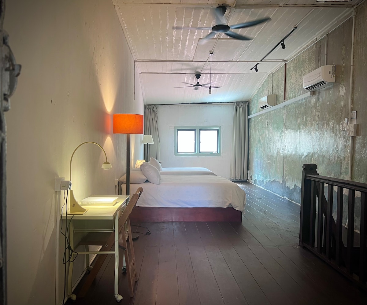 ห้องนอนขนาดใหญ่และโปร่งสบาย มีเตียงควีนไซส์ 2 เตียง พื้นไม้สีอบอุ่น ผนังสีเขียวอ่อนดั้งเดิมที่ถูกขูดออกมา แสงแดดส่องผ่านหน้าต่างเข้ามาเต็มที่ มีโต๊ะทำงาน โคมไฟอ่านหนังสือ และผ้าม่านสีดำ