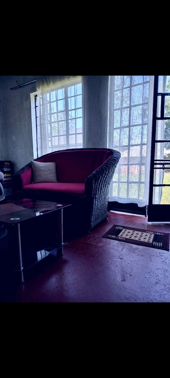 A cozy corner is highlighted by a comfortable wicker chair with a soft cushion. Natural light filters through large windows, creating a bright space. A small coffee table is positioned nearby, adding functionality to the inviting seating area.