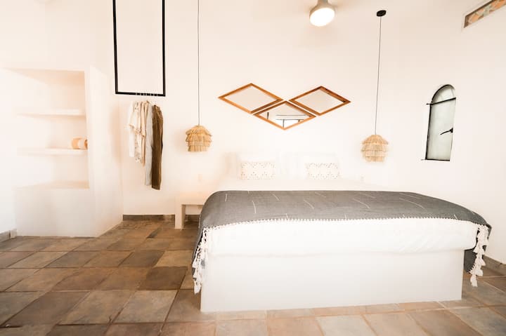 这间卧室线条简洁，采用温暖的木质装饰，配有一张加大双人床、悬浮吊灯和装饰镜面板。
