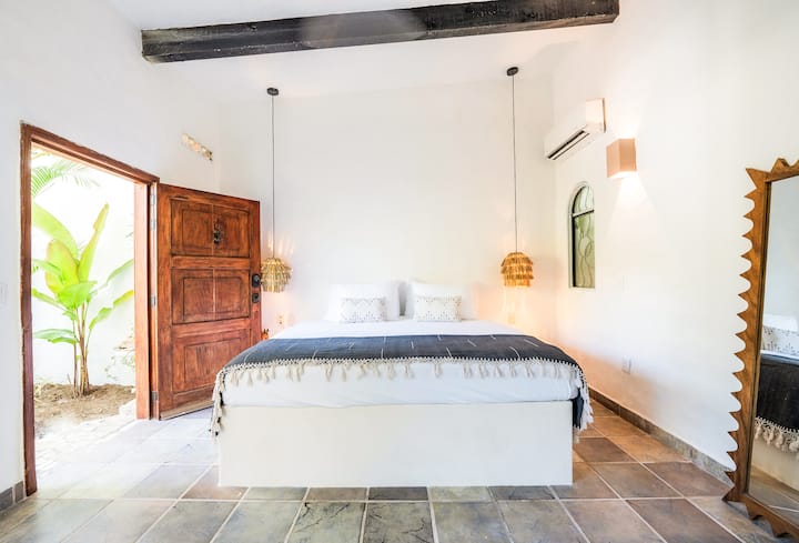 这间卧室融合了乡村风情和通风良好的开放式布局，可轻松连接户外。 柔和的灯光和自然的纹理营造出一个宁静的空间，非常适合缓慢的早晨和长期住宿。