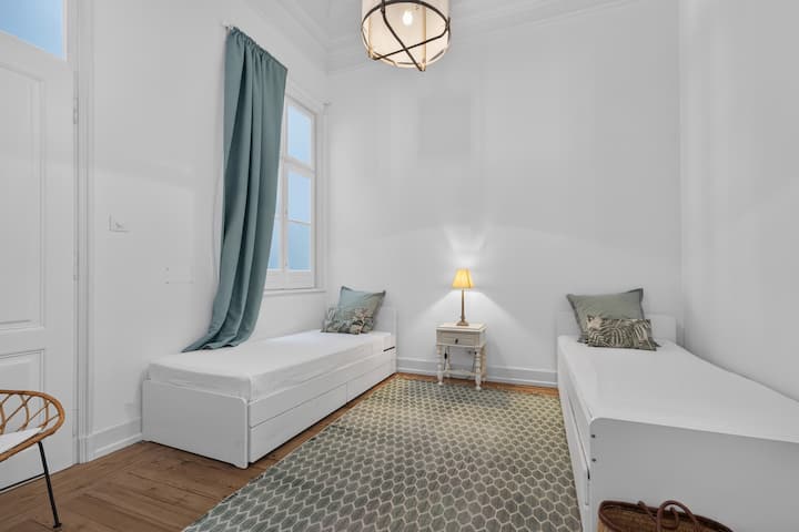 Bright twin bedroom with high ceilings and a calm, airy design