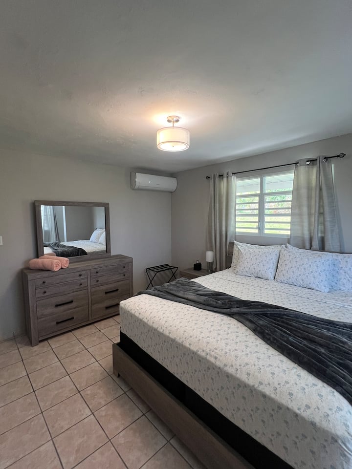 Glavna spavaća soba s klima-uređajem, stalkom za prtljagu i punjačem tipa C na noćnom ormariću.