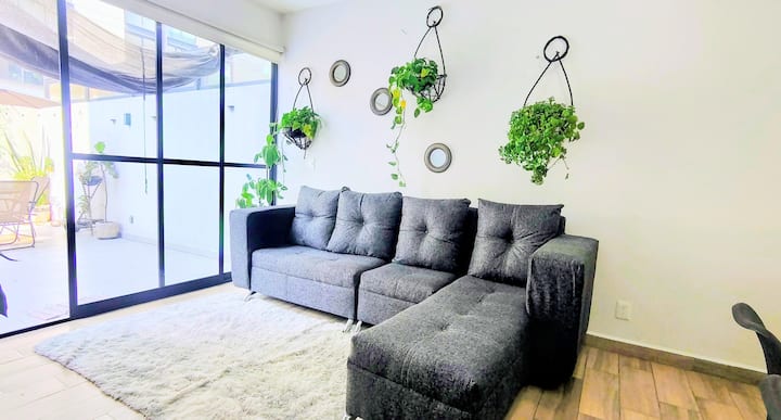 Sala moderna y acogedora, con amplio sofá en L, ideal para descansar, ver TV o convivir en un ambiente cómodo y relajado.