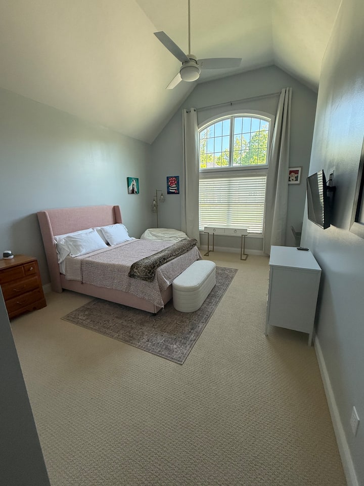 Large bedroom with vaulted ceilings. Queen bed with mounted TV. Keyboard piano.