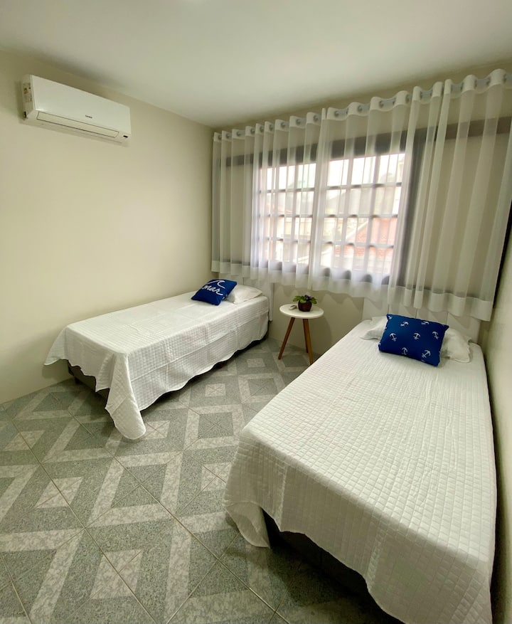 Chambre avec deux lits simples et deux matelas simples avec climatisation et armoire. 