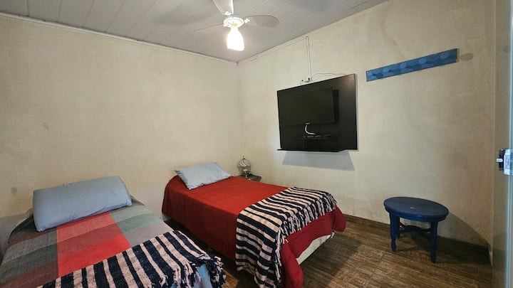 Una suite tranquilla con un letto singolo matrimoniale reversibile, TV da 32", atmosfera accogliente e ventilatore a soffitto.  Entrambe le suite sono indipendenti e direttamente accessibili al balcone con amache.​ Goditi privacy e comfort in tutta tranquillità