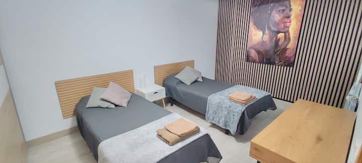 Dormitorio amplio con dos camas individuales y armario.
