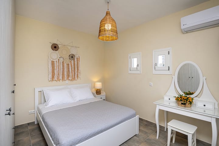 Retreat to this serene bedroom on the upper floor where bohemian charm meets coastal elegance. The artisanal woven pendant casts a golden glow over crisp linens, while the handcrafted macramé wall hanging adds artistic flair. 