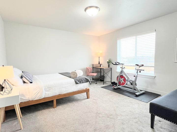 This bedroom has a queen bed, work desk, workout equipment, an en-suite full bathroom, and walk in closet.