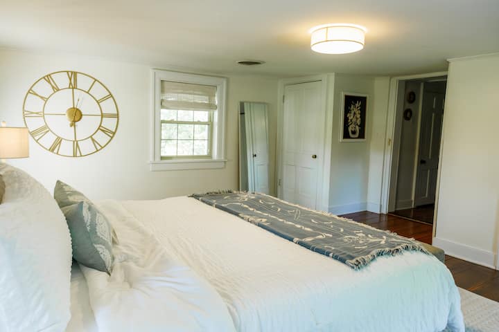 Light filled bedroom with a full size mirror and a tv for movie nights. 