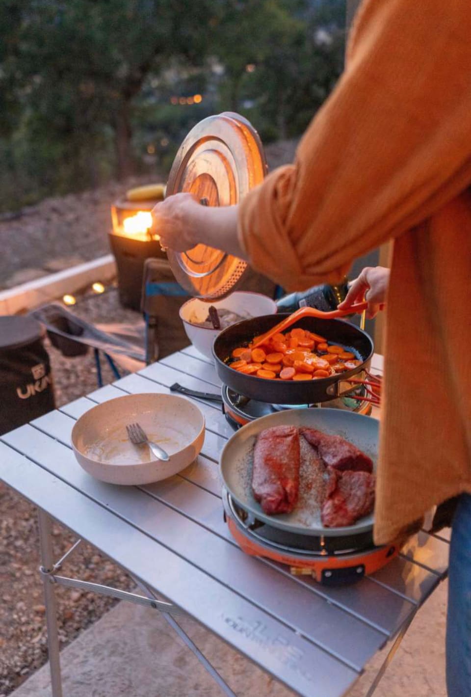 A guest makes dinner using her own camping gear in the friendly SHARED kitchen that is utilized by the host, cohost, other guests. We have stoves, utensils, pans and more if you wa