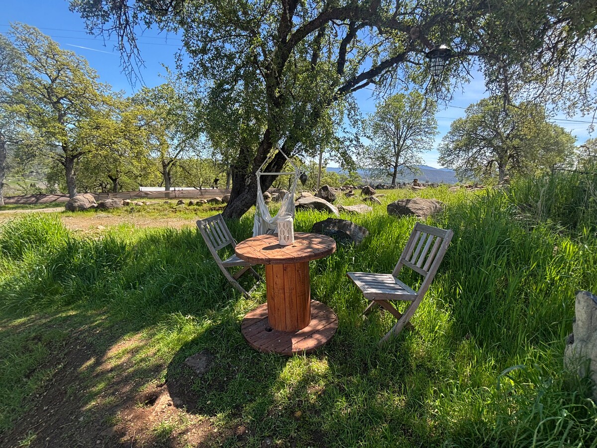 At your campsite …The shady tree and spool table with teak chairs and boho hanging hammock chair on your glamping site. at Bohemian Belle Yurt in Hidden Valley Lake