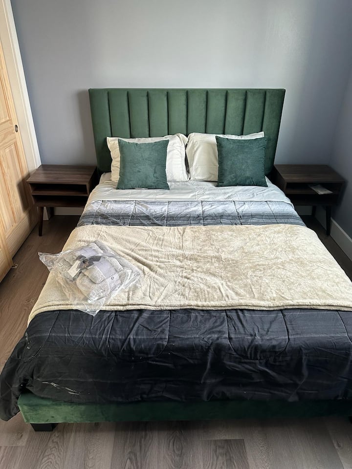 Un armario personal acompaña a una cama tamaño queen, que se completa con un ventilador para mayor comodidad.