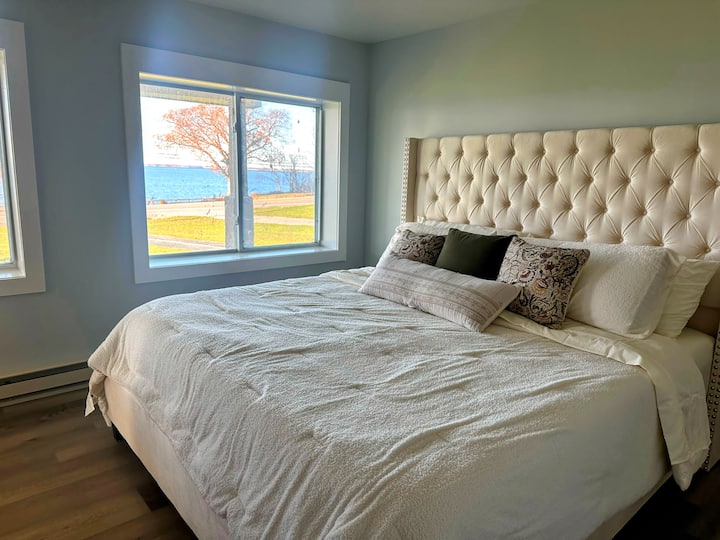 En el primer nivel, el dormitorio 1 cuenta con un espacioso dormitorio principal con una cama tamaño king y un baño privado. Disfruta de impresionantes vistas del río St. Lawrence a través de grandes ventanales.

