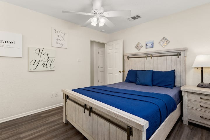 Rest easy in a peaceful primary bedroom with a queen bed, soft lighting, and plenty of space to unwind after a full day by the Guadalupe River.