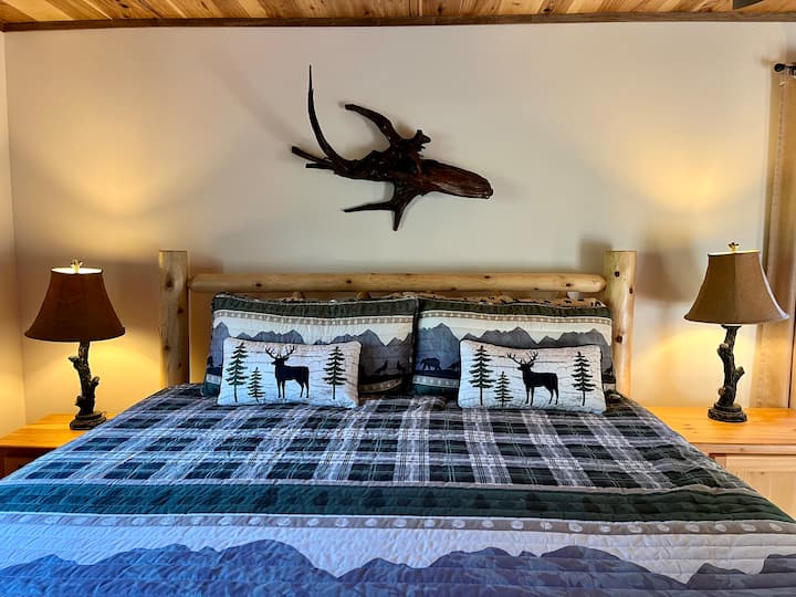 Spálňa s manželskou posteľou King na poschodí.  Zobrazené Driftwood je z brehu jazera.