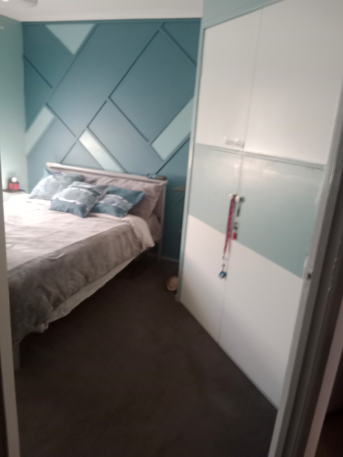 בחדר השינה יש מיטה זוגית, מדפים, מלתחה, פופה וטלוויזיה