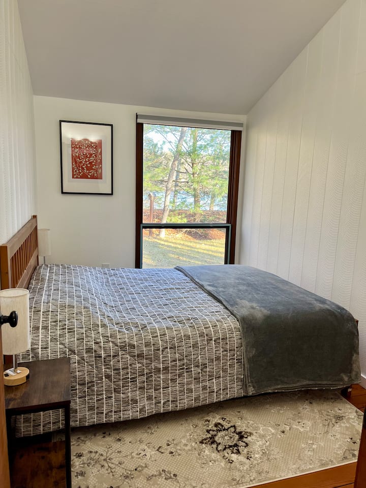 Dormitorio con vista al lago y cama tamaño queen