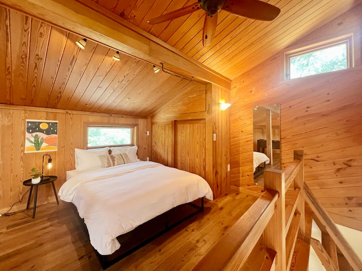 Accedido por escaleras de madera, el dormitorio del loft es la habitación más cálida de la casa, que exuda una verdadera sensación de cabaña rodeada de paneles de madera. Está amueblado con una cama tamaño queen.