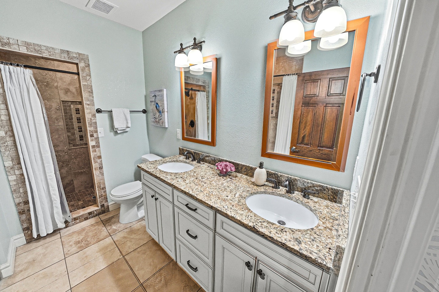 Spacious ensuite bathroom featuring a double vanity, walk-in shower, a jetted tub/shower combo and plenty of room to get ready after a relaxing beach day.