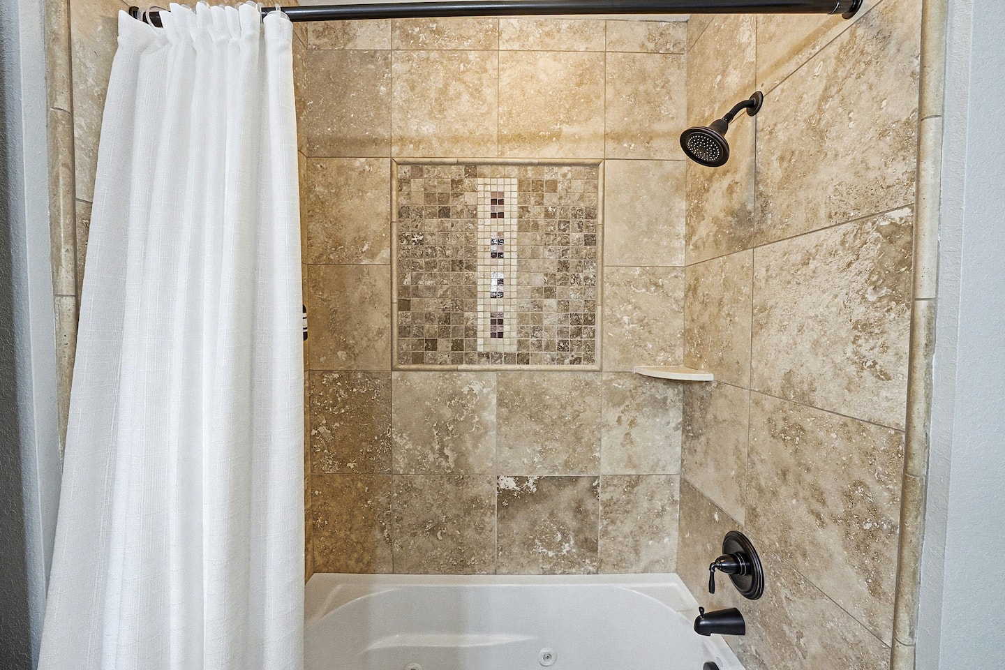 Beautiful tiled shower with upgraded fixtures and custom accent tile details for a relaxing retreat feel.