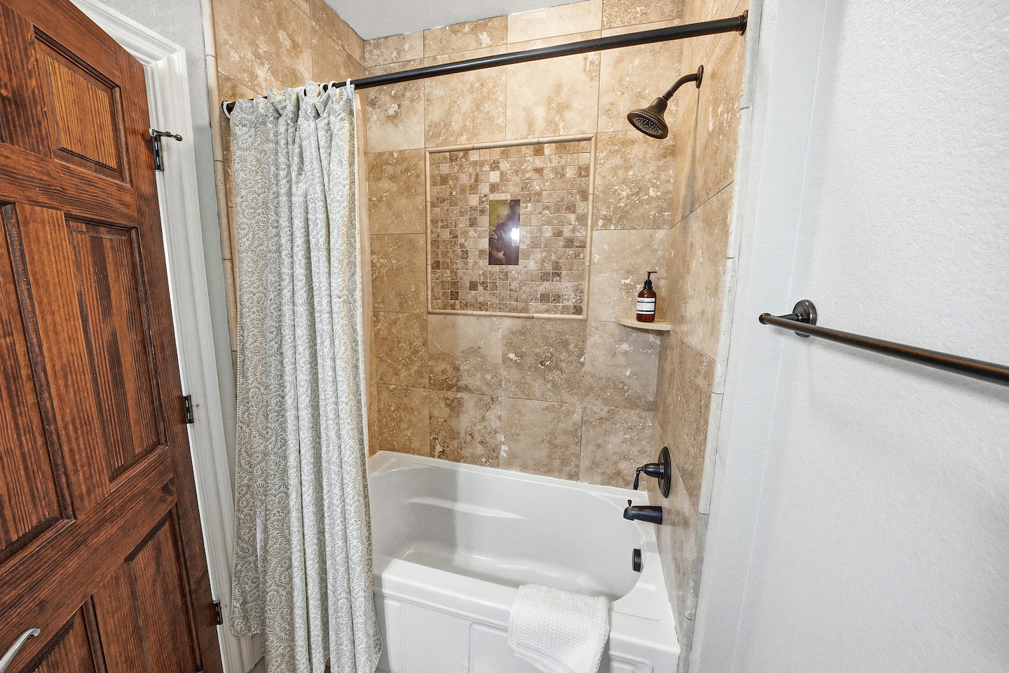 Family-friendly ensuite bathroom featuring a beautifully tiled shower/tub combo with upgraded finishes and relaxing coastal touches.