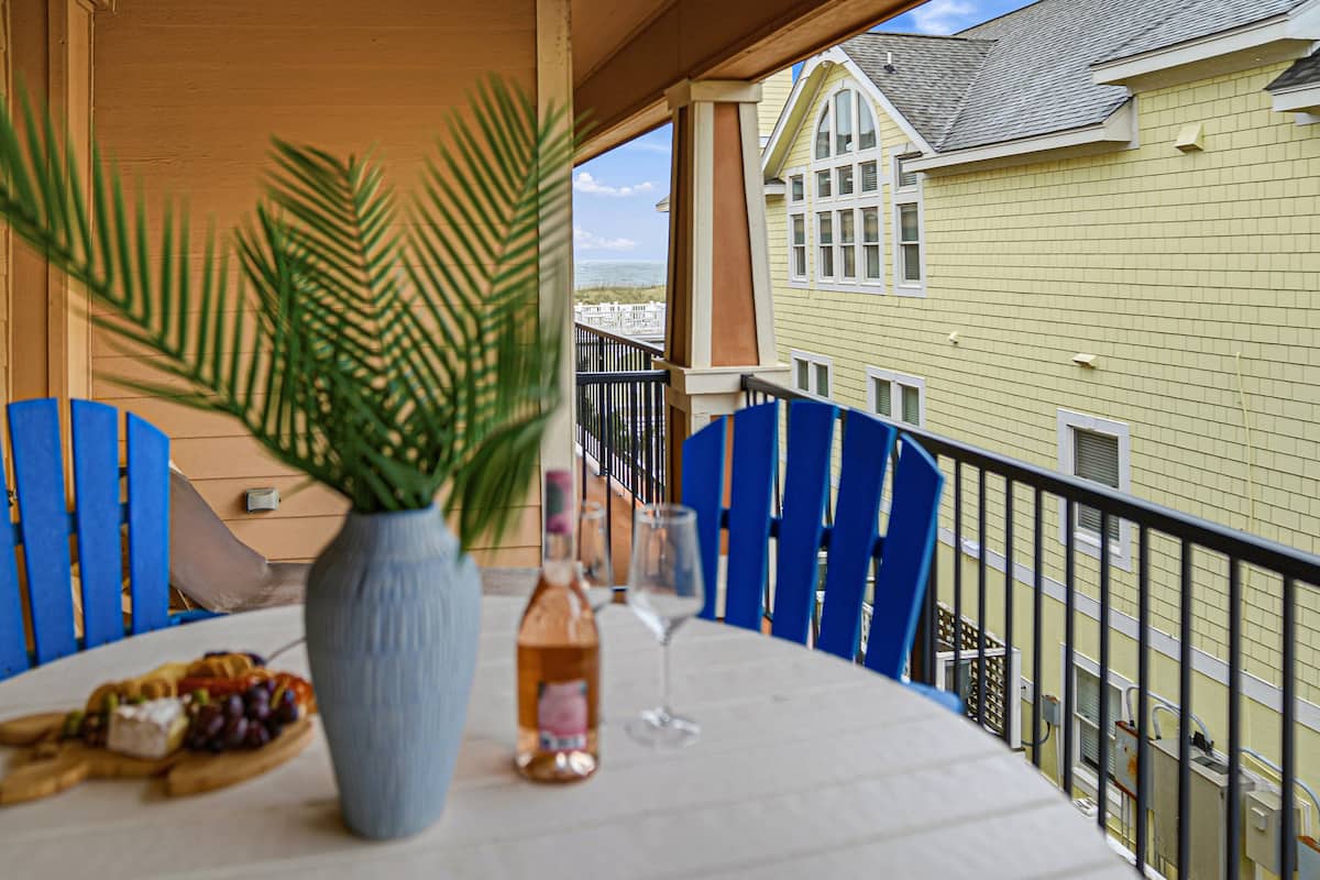 Covered balcony with cushioned seating and partial ocean views over the Croatan Surf Club grounds